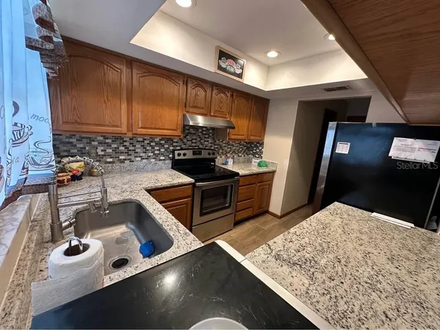 a kitchen with stainless steel appliances granite countertop a sink stove and refrigerator