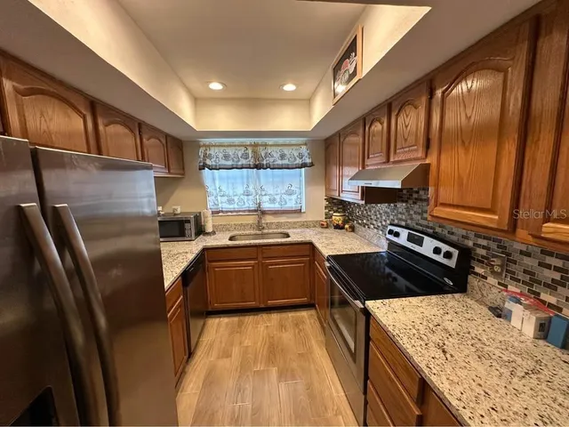 a kitchen with stainless steel appliances granite countertop a refrigerator a stove and a sink