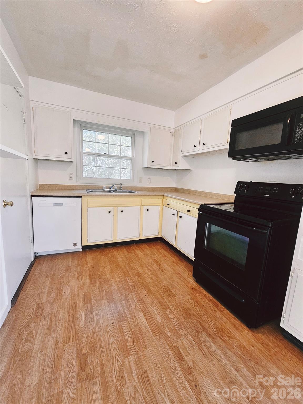 468 Beaverdam Road Asheville, NC 28804 - Photo 14 of 19 a large kitchen with granite countertop a stove top oven a sink dishwasher and white cabinets with wooden floor