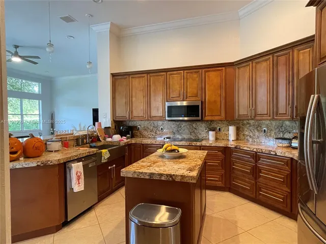 a kitchen with stainless steel appliances granite countertop a stove a sink dishwasher and a refrigerator with wooden cabinets