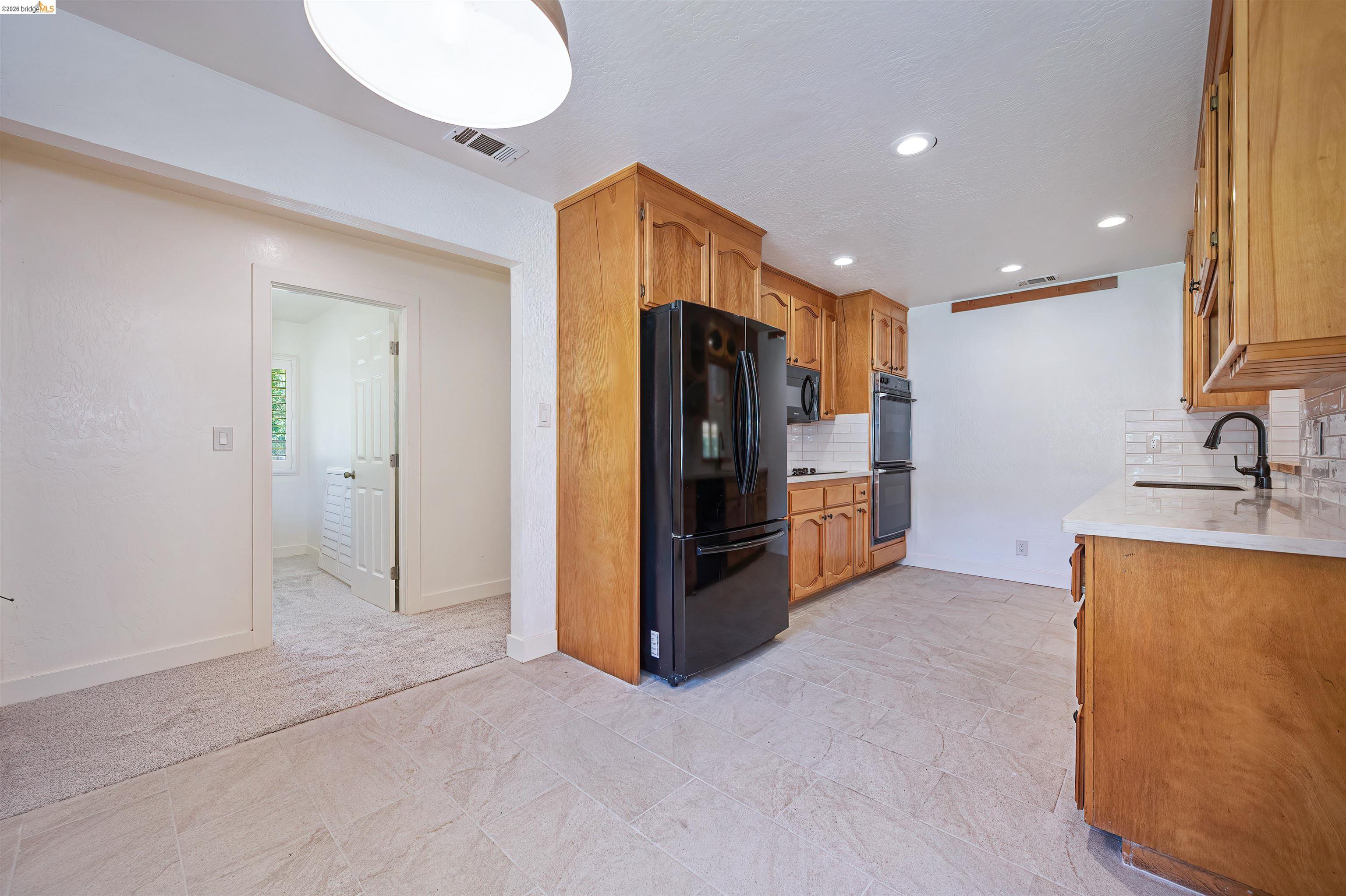 10474 Sheldon Road Elk Grove, CA 95624 - Photo 19 of 83 Kitchen featuring warm wood cabinetry, white subway tile backsplash, and light-toned tile flooring