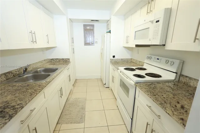 a kitchen with granite countertop a sink stove and cabinets