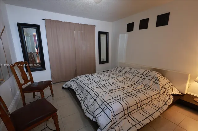 a bedroom with a bed a chair and a large mirror