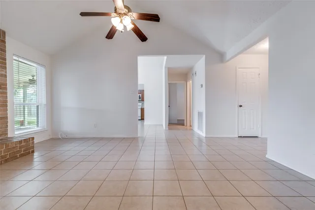 an empty room with chandelier fan and windows