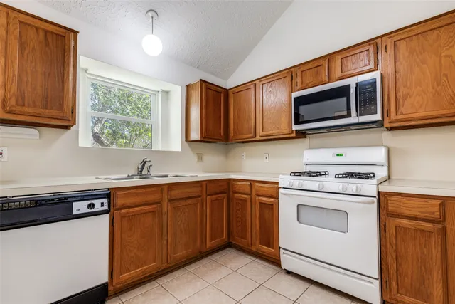 a kitchen with stainless steel appliances granite countertop a stove top oven a sink dishwasher and white cabinets with wooden floor