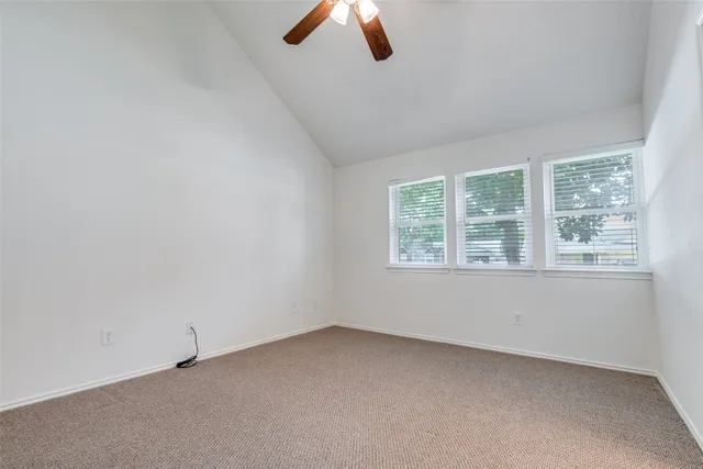 an empty room with windows and ceiling fan