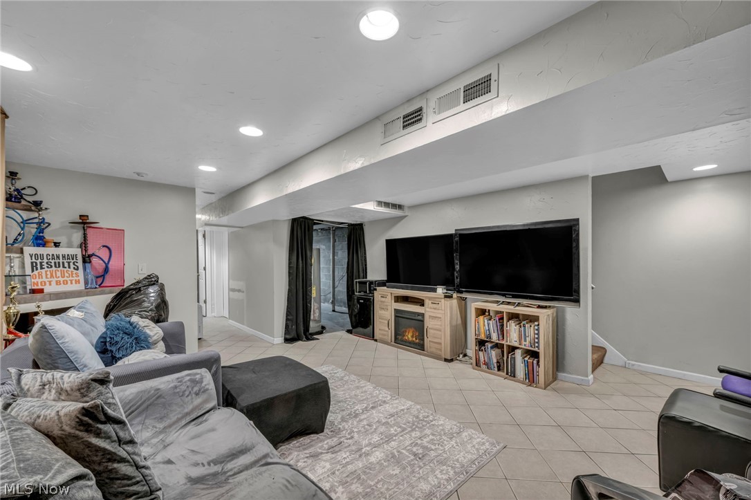 13800 Milo Road Garfield Heights, OH 44125 - Photo 22 of 39 Living area featuring light tile patterned floors, a glass covered fireplace, and recessed lighting
