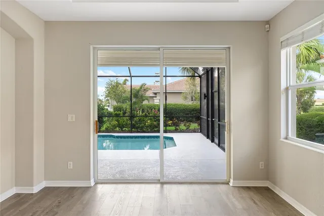 a view of an empty room with a window and wooden floor