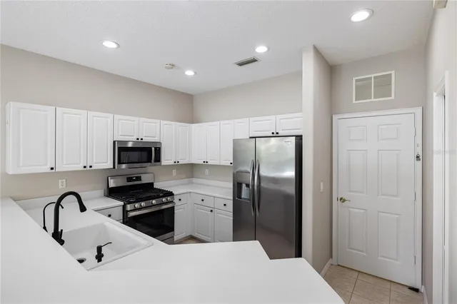 a kitchen with stainless steel appliances granite countertop a refrigerator a stove a sink a stove a microwave and a refrigerator with wooden floor