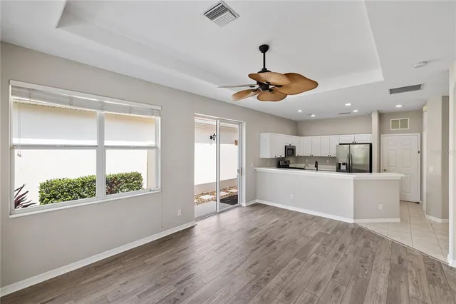 a view of a kitchen and an empty room with wooden floor and windows