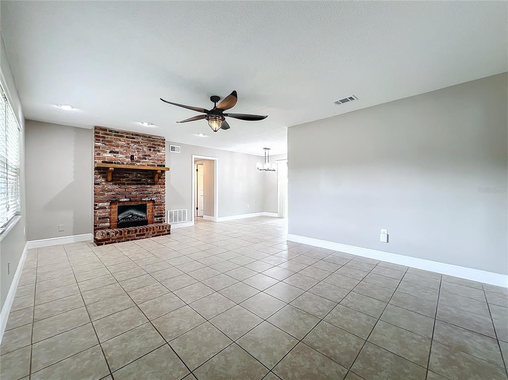 600 Ridgefield Avenue Ocoee, FL 34761 - Photo 10 of 45 Electric Fireplace in living room with ceramic tile floors, upgraded baseboards, new ceiling fan and insulated beveled glass front door opens to dinging area and kitchen.