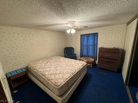 Bedroom featuring a textured ceiling, ceiling fan, and dark carpet