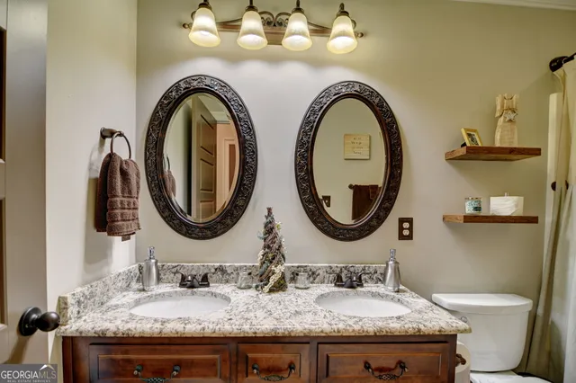 a bathroom with a granite countertop toilet a sink and a mirror