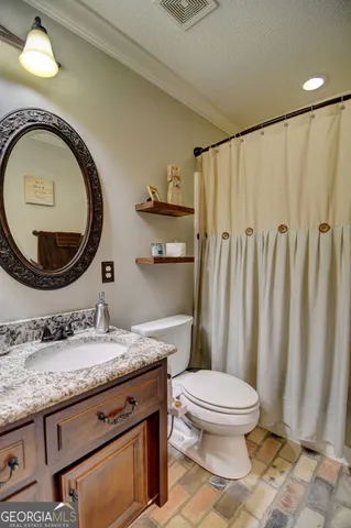 a bathroom with a granite countertop bathtub sink vanity mirror and toilet