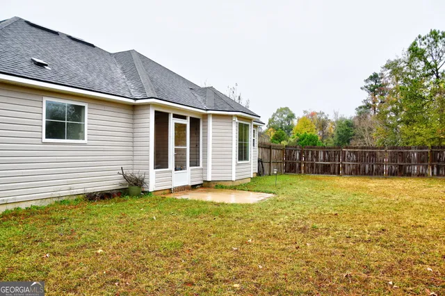 a view of a house with a yard and a large tree