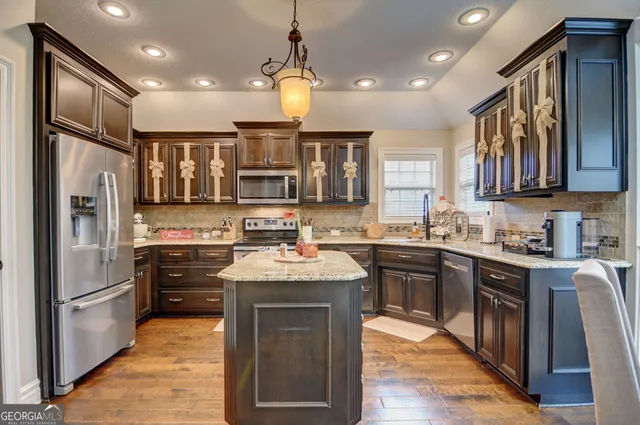 a kitchen with stainless steel appliances granite countertop a sink stove refrigerator and cabinets