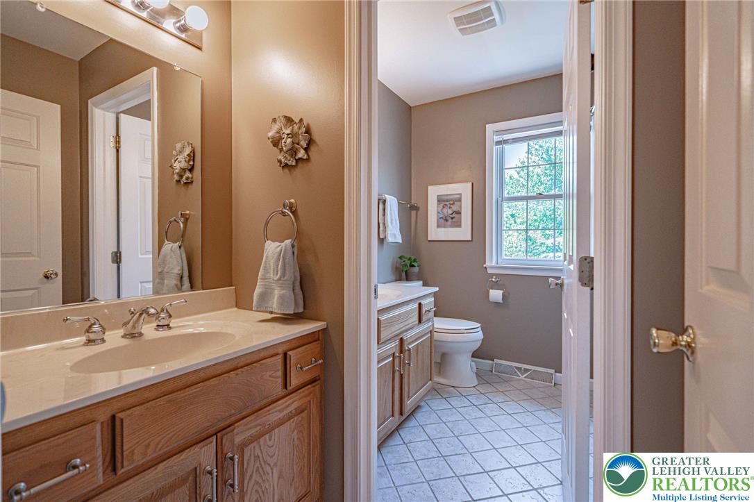 4542 Springfield Drive Coplay, PA 18037 - Photo 53 of 89 A classic bathroom vanity with ample counter space and well-lit mirror stands adjacent to a tiled floor, offering convenience and appeal.