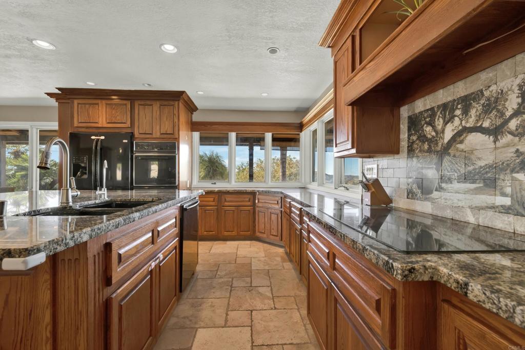 29345 Wilkes Road Valley Center, CA 92082 - Photo 59 of 63 a kitchen with stainless steel appliances granite countertop a sink a stove and a wooden cabinets