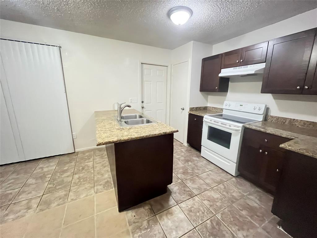575 Manco Road, Unit A Lewisville, TX 75067 - Photo 3 of 9 a kitchen with stainless steel appliances granite countertop a stove a sink and a microwave