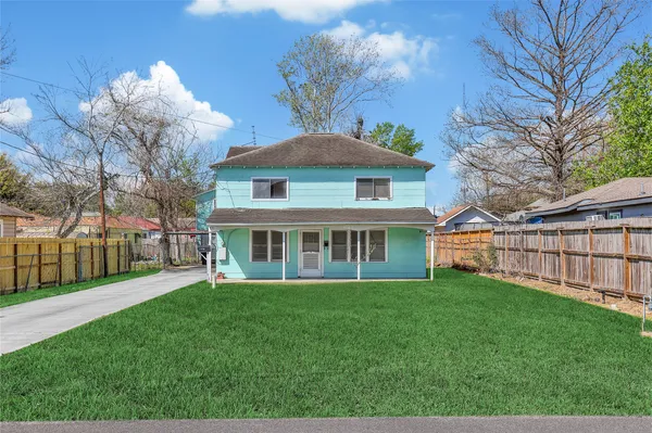 a view of a house next to a big yard and large trees