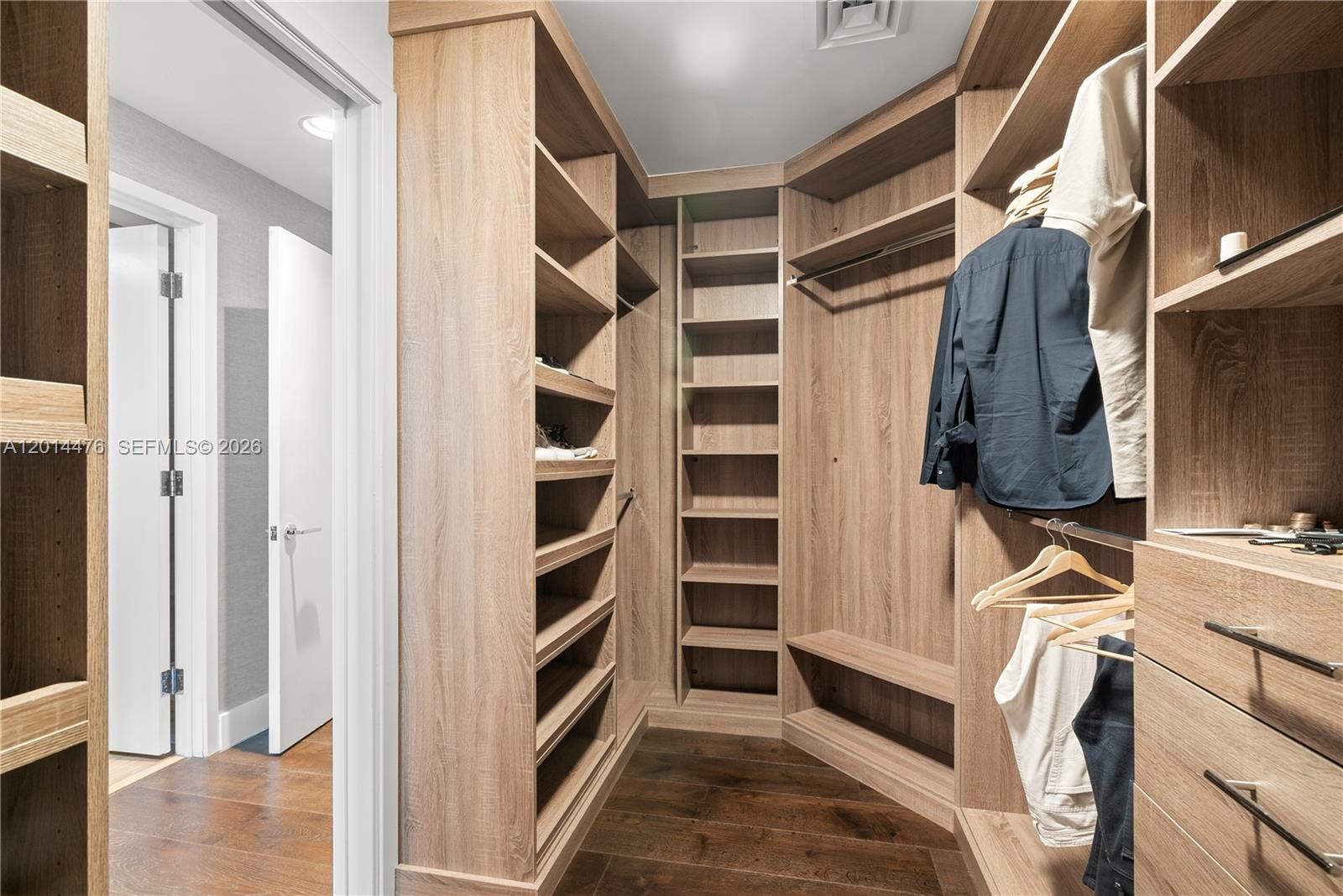 360 Ocean Drive, Unit 1106S Key Biscayne, FL 33149 - Photo 25 of 67 Walk-In Closet – The custom walk-in closet is designed with extensive open shelving, hanging areas, drawers, and built-in storage. Wood finishes and a generous layout create a polished, boutique-style organization space.