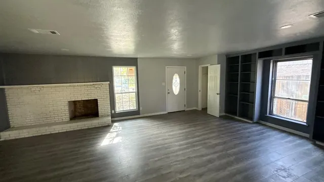 an empty room with wooden floor and fireplace