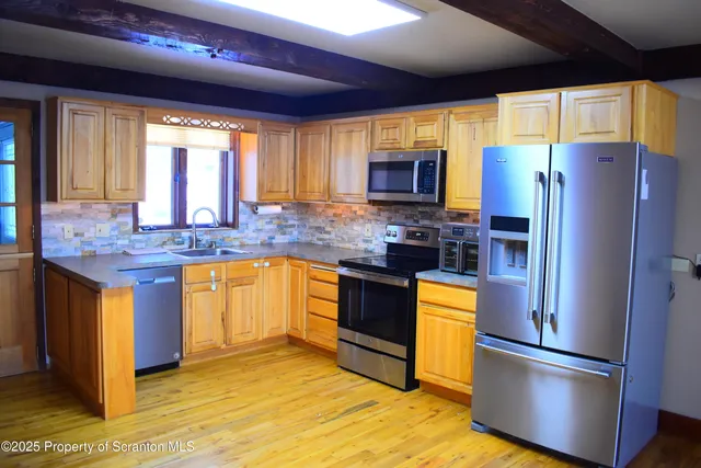 a kitchen with stainless steel appliances granite countertop a refrigerator a stove top oven a sink and dishwasher
