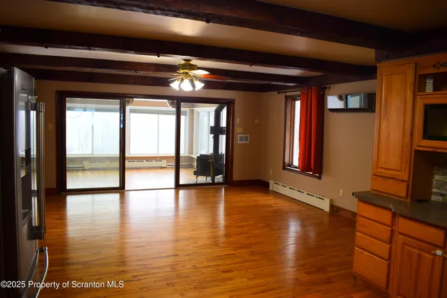 a view of an empty room with window and wooden floor