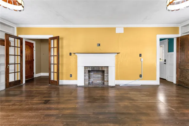 a view of an empty room with wooden floor and a fireplace