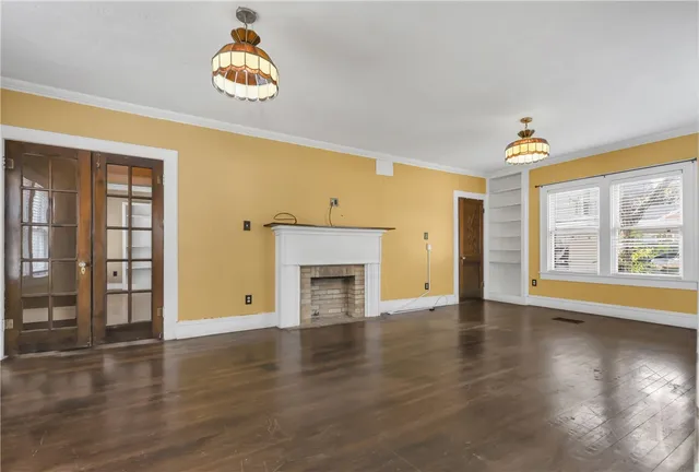 an empty room with wooden floor chandelier and windows