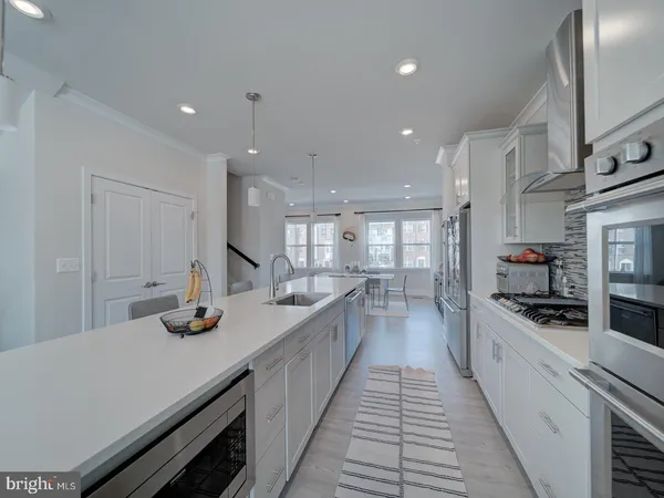 a large kitchen with kitchen island a stove a sink a refrigerator and white cabinets