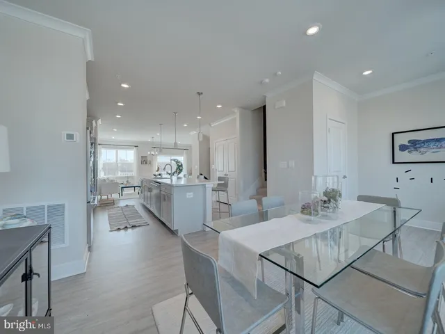 a kitchen with a dining table chairs wooden floor appliances and cabinets
