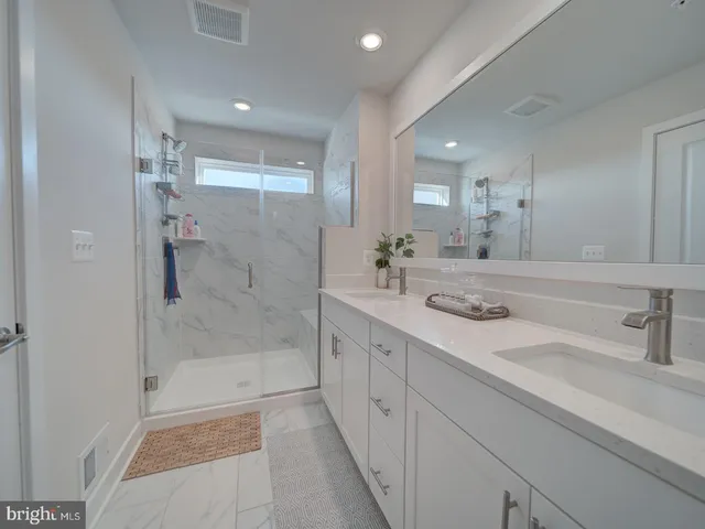 a bathroom with a double vanity sink mirror and shower
