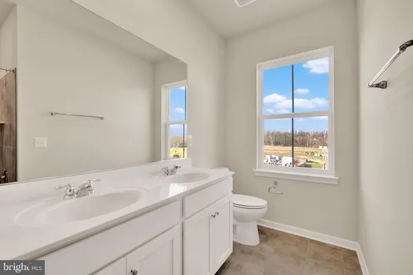 a bathroom with a granite countertop sink a toilet and a window