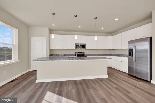 a large kitchen with stainless steel appliances granite countertop a large counter top a sink and a refrigerator