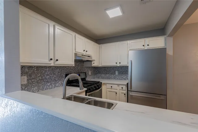 a kitchen with a refrigerator and white cabinets