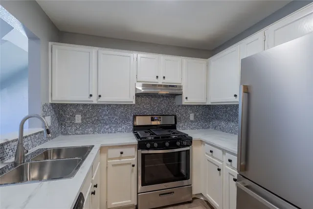 a kitchen with granite countertop a sink stove and refrigerator