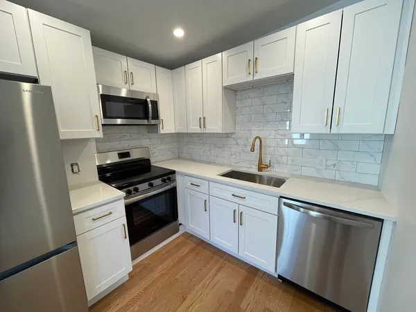 a kitchen with stainless steel appliances white cabinets a sink a stove a refrigerator and white cabinets