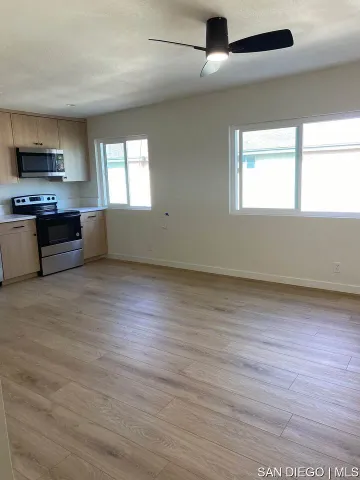 an empty room with wooden floor cabinet and windows