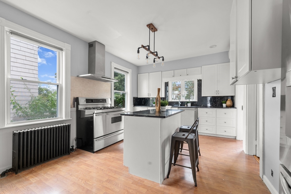 29 Garnet Road Boston, MA 02132 - Photo 13 of 42 a kitchen with a refrigerator a stove a sink dishwasher a dining table and chairs with wooden floor