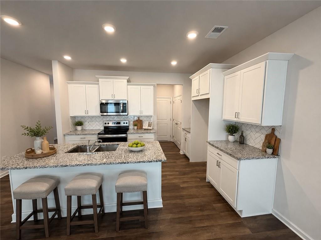 5151 Longview Run Decatur, GA 30035 - Photo 5 of 24 a kitchen with stainless steel appliances granite countertop a stove top oven a refrigerator a sink and a dining table with wooden floor