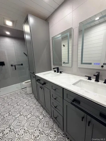 a spacious bathroom with a double vanity sink a large mirror and a shower