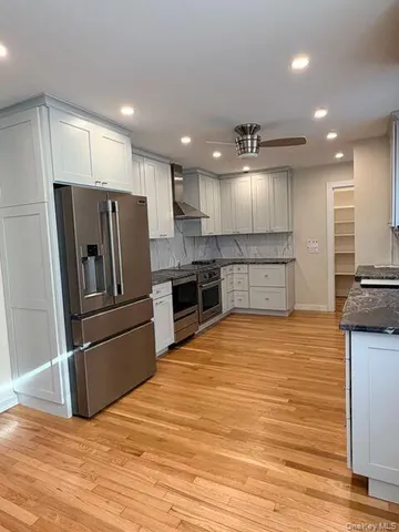a large kitchen with kitchen island a large counter top stainless steel appliances and cabinets