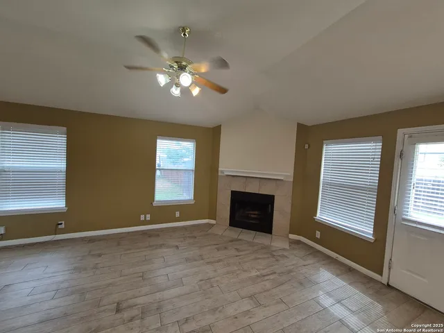 an empty room with windows and fireplace