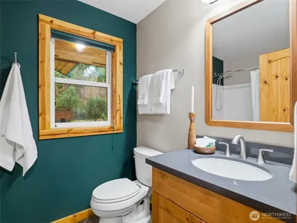 a bathroom with a granite countertop sink toilet and mirror