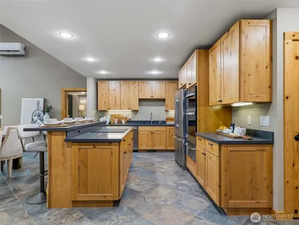 a kitchen with kitchen island granite countertop wooden cabinets stainless steel appliances a sink and a center island