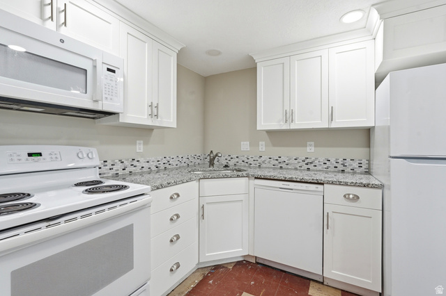 778 East 200 North Logan, UT 84321 - Photo 14 of 43 Kitchen featuring white cabinetry with brushed nickel hardware, light-toned countertops, a mosaic tile backsplash, and white appliances including a range, microwave, and dishwasher