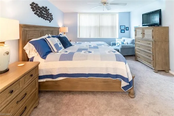 a spacious bedroom with a bed and a flat tv screen on dresser