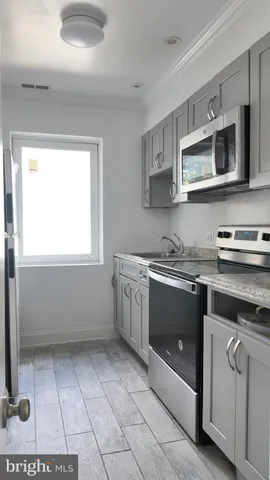 a kitchen with stainless steel appliances a stove a microwave and white cabinets