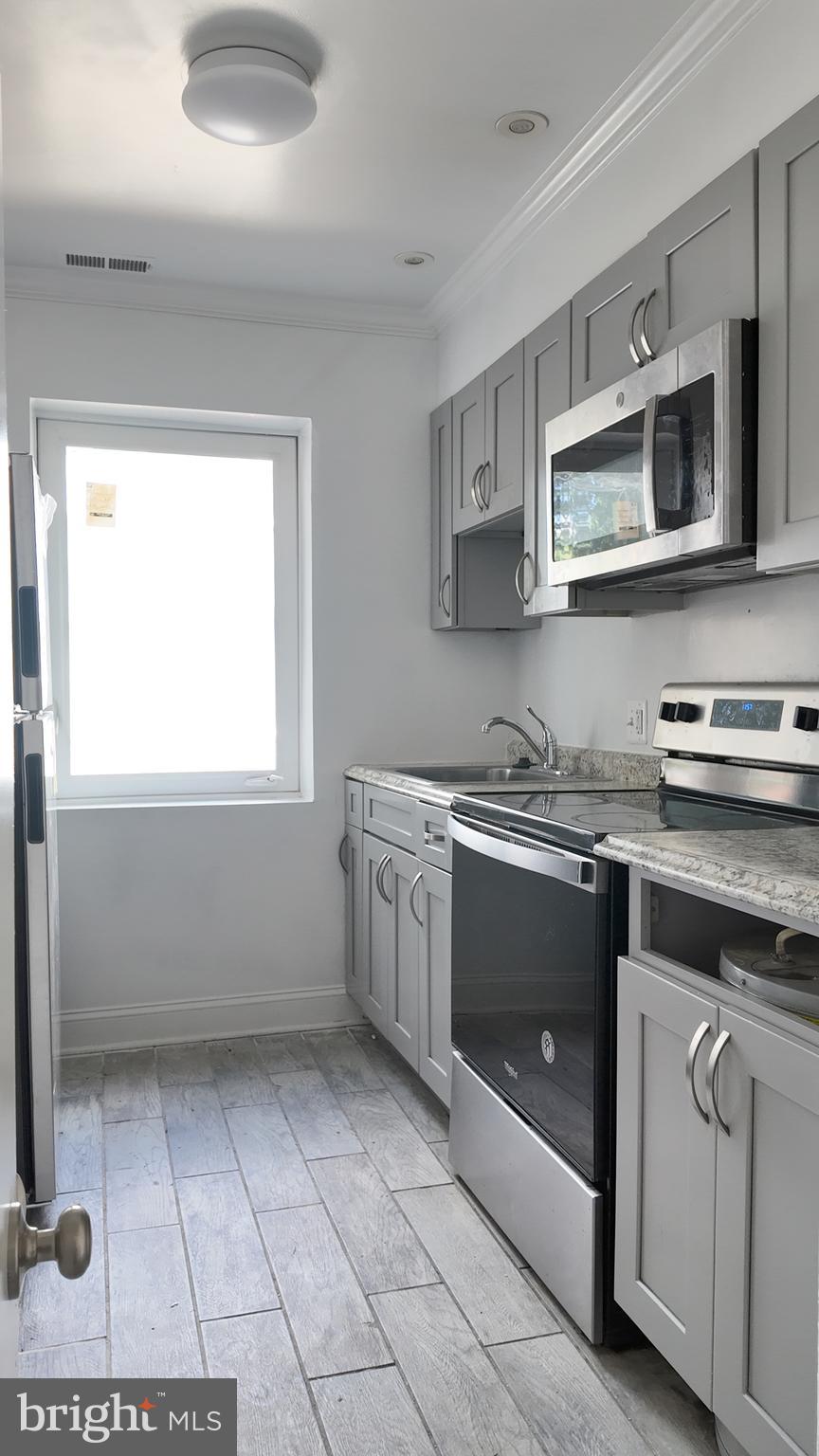 4306 Halley Terrace Southeast, Unit 1 Washington, DC 20032 - Photo 4 of 9 a kitchen with stainless steel appliances a stove a microwave and white cabinets